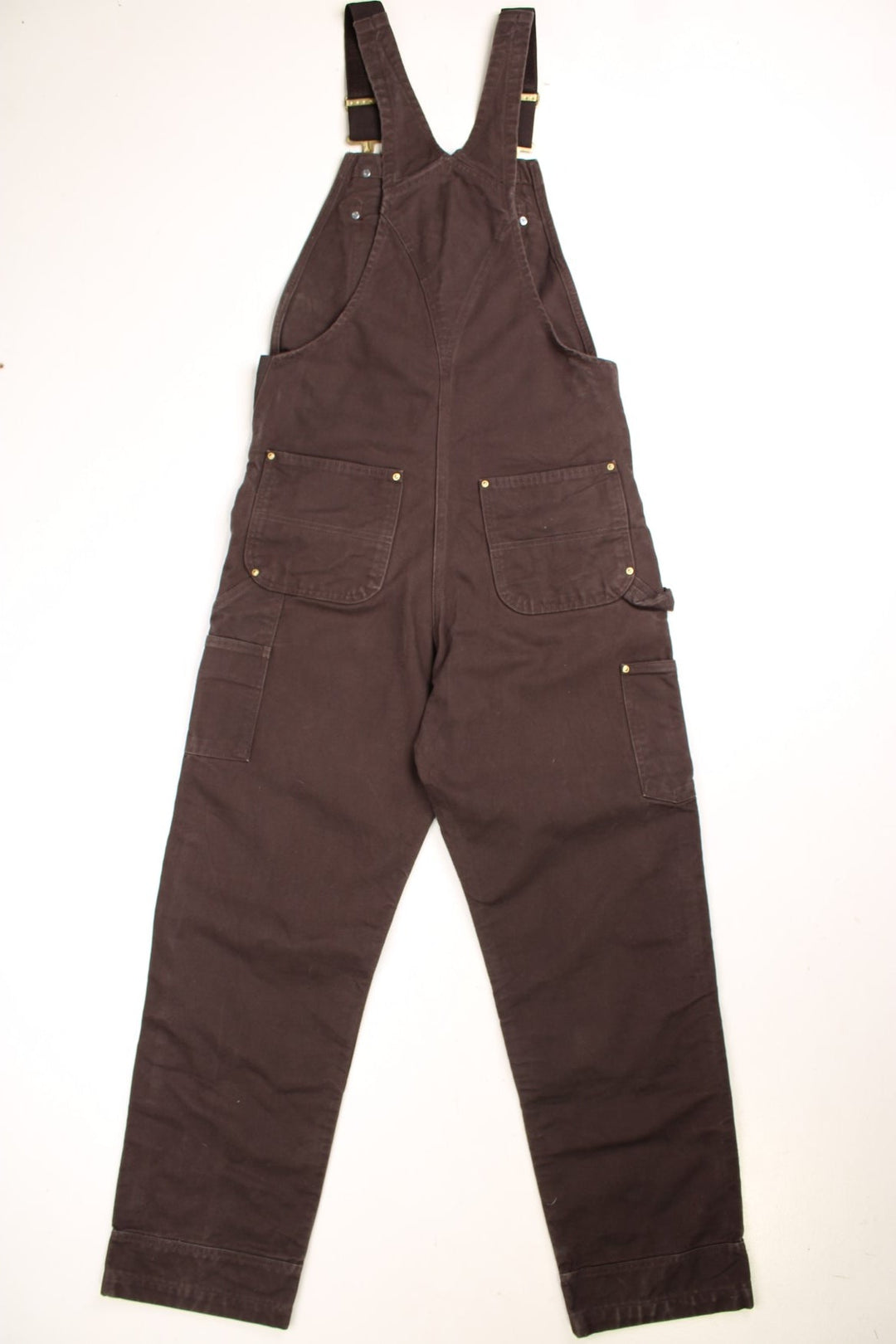 Carhartt carpenter-style dungarees in brown with black straps, multiple pockets, and a logo patch.