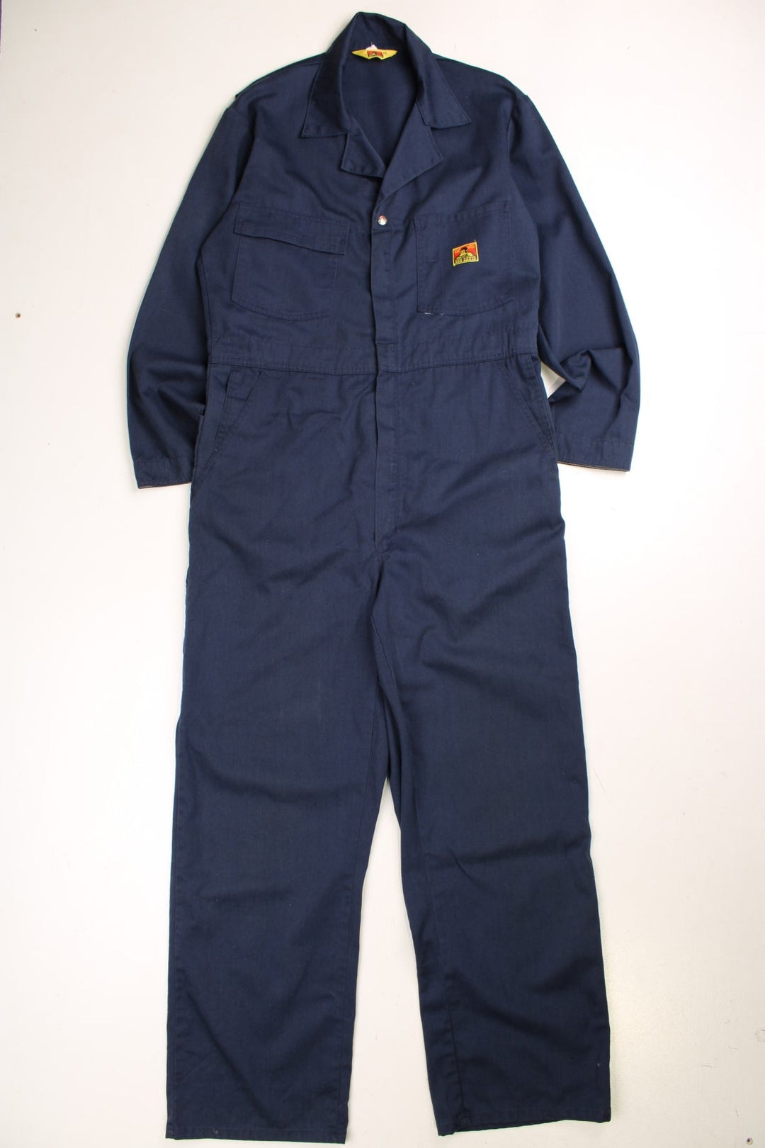 Ben Davis long-sleeved boiler suit/overalls in navy blue with multiple pockets, zip and button closure.