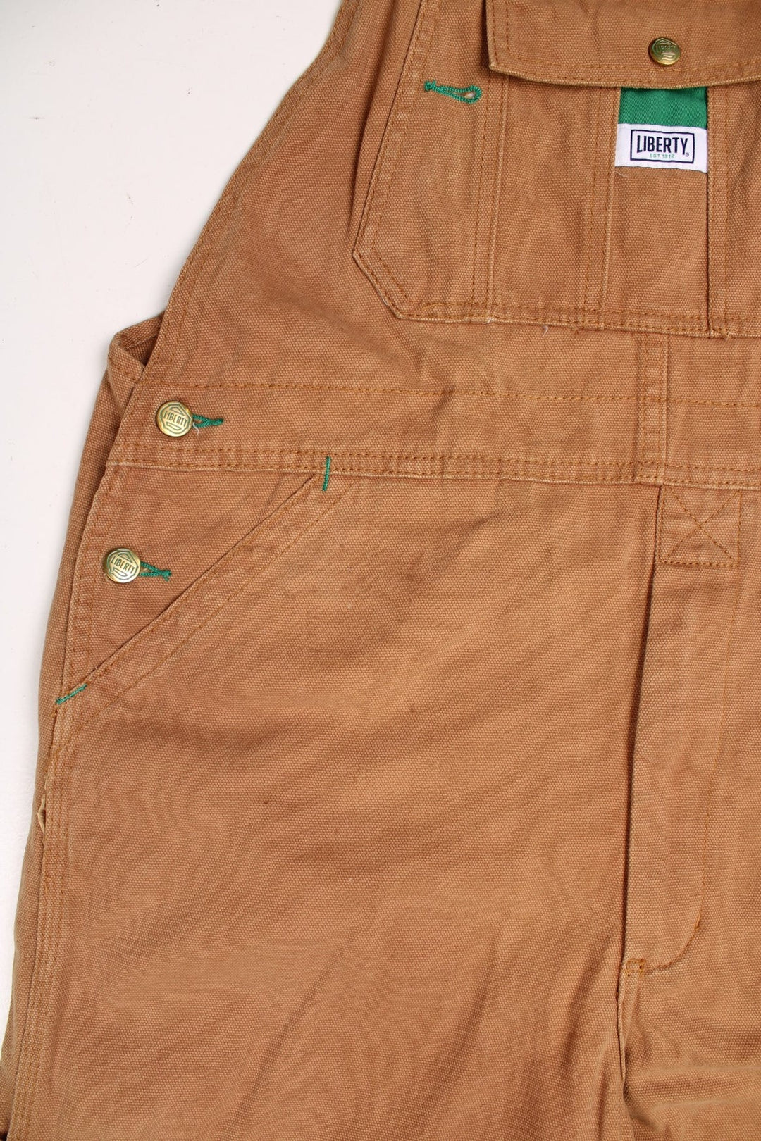 Tan Liberty dungarees with green accents, multiple pockets, logos front and back. 