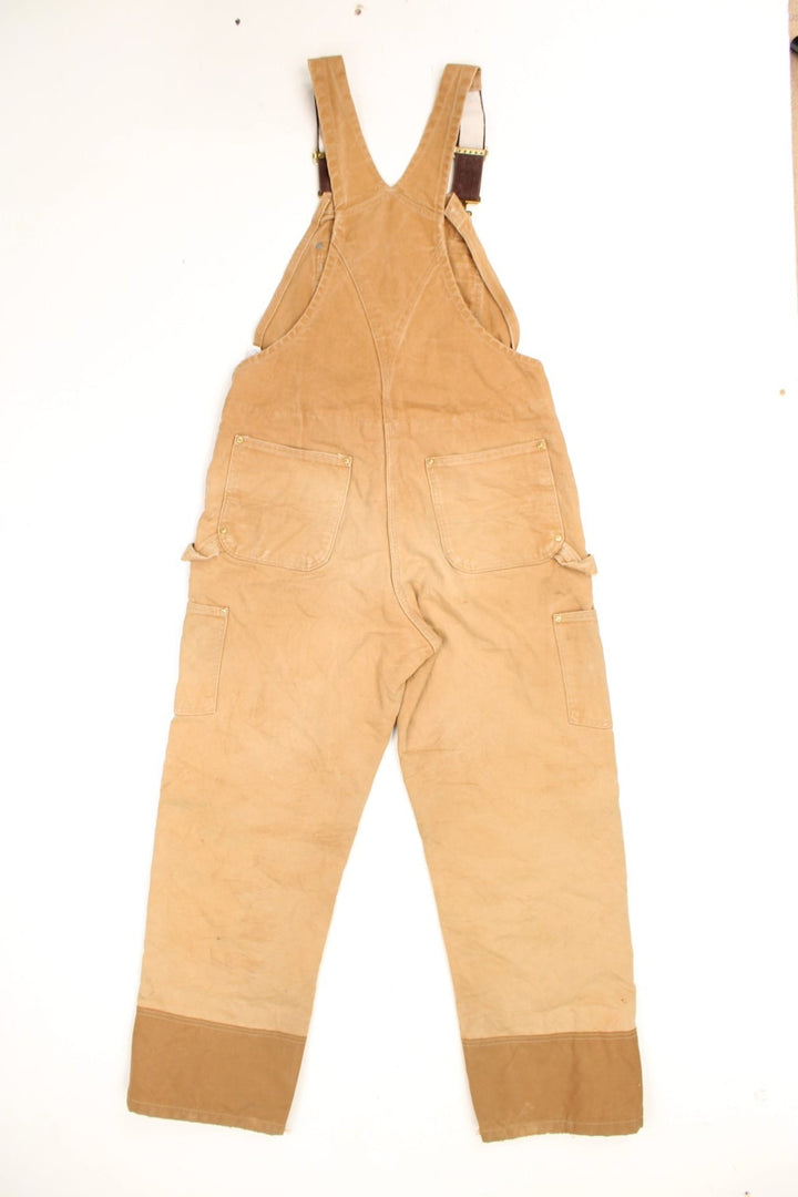 Carhartt double knee quilt lined bib overalls/dungarees. Features multiple pockets, embroidered logo and zip and popper fastening up both legs.