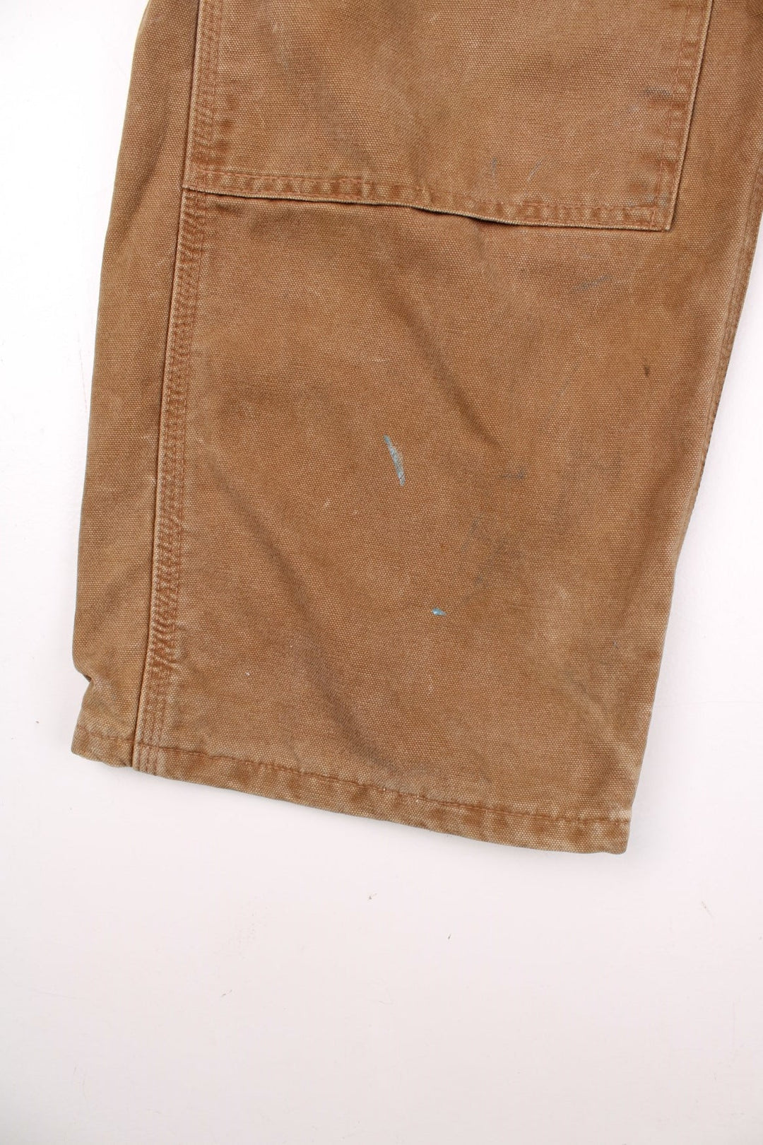 Carhartt carpenter-style dungarees in tan with multiple pockets  red-brown elasticated straps, and a leather logo patch on the front.