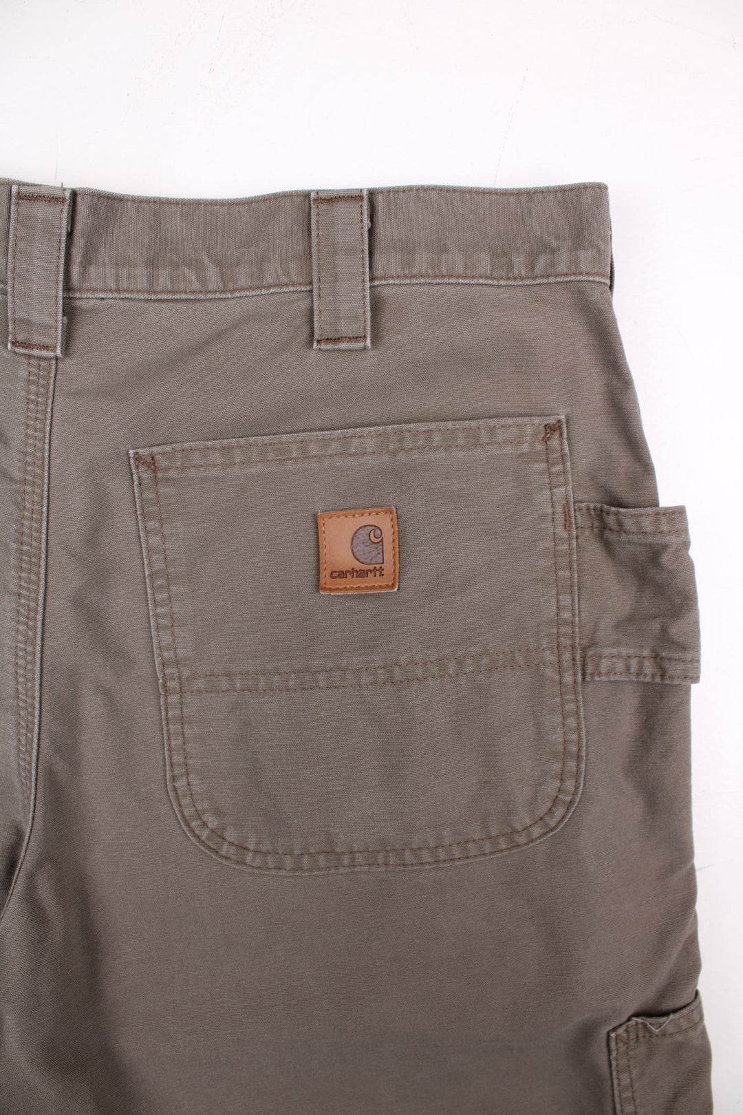 Carhartt shorts in khaki with multiple pockets, zip and button closure, and a leather logo patch on the back.