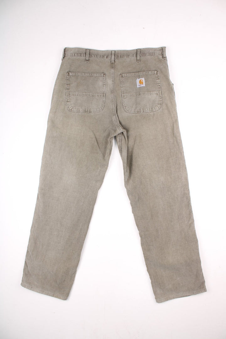 Carhartt corduroy trousers in tan with multiple pockets, zip and button closure, and a logo patch on the back pocket.