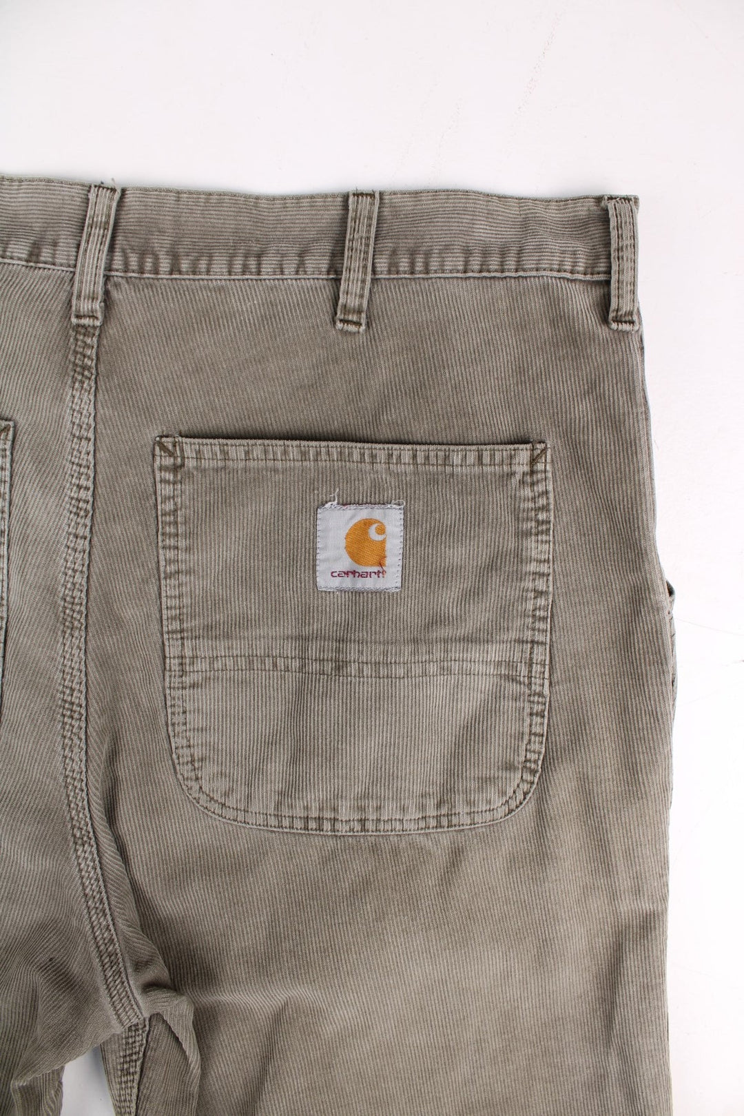 Carhartt corduroy trousers in tan with multiple pockets, zip and button closure, and a logo patch on the back pocket.