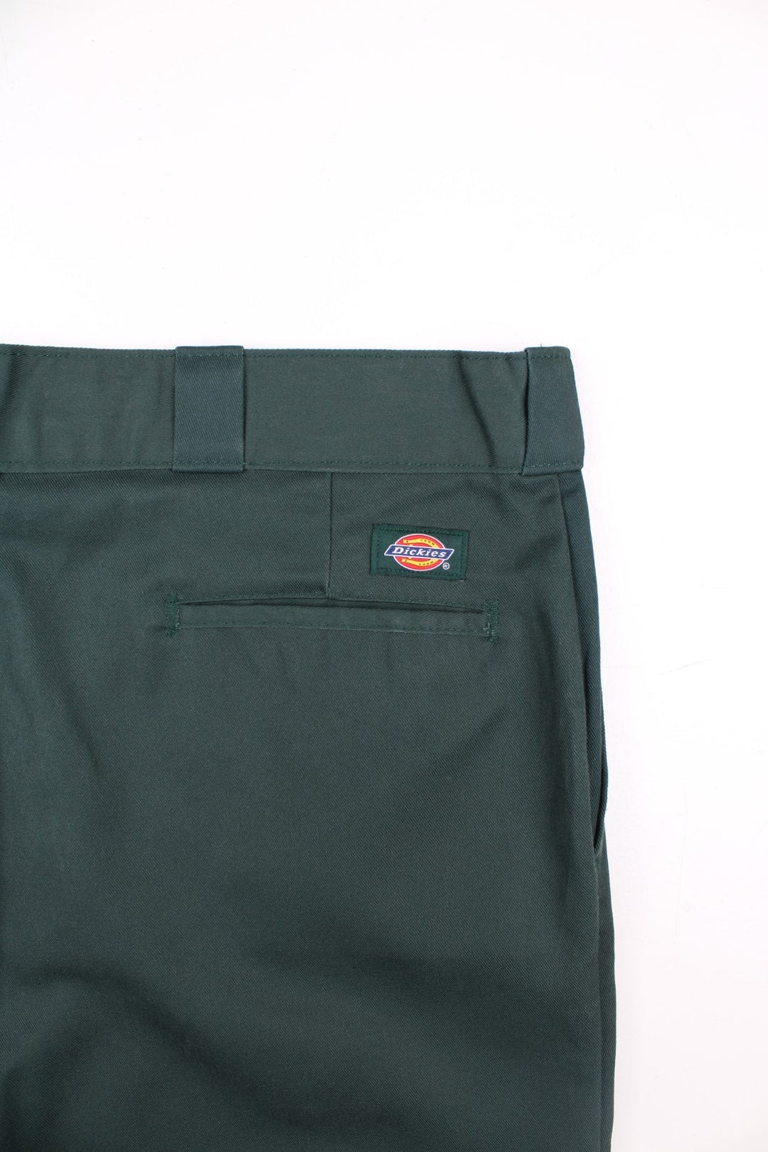 Dickies work trousers in green with multiple pockets, zip and button closure, and a logo patch on the back.