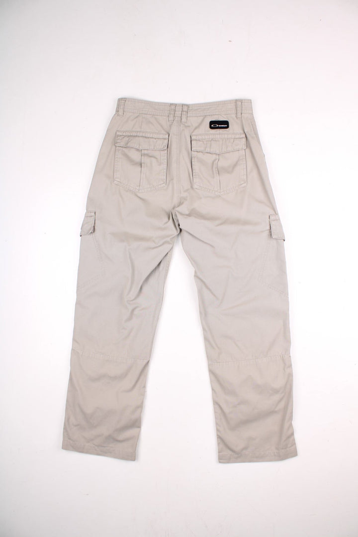 Oakley cargo trousers in tan with multiple pockets, zip and button closure, and a logo patch on the back.