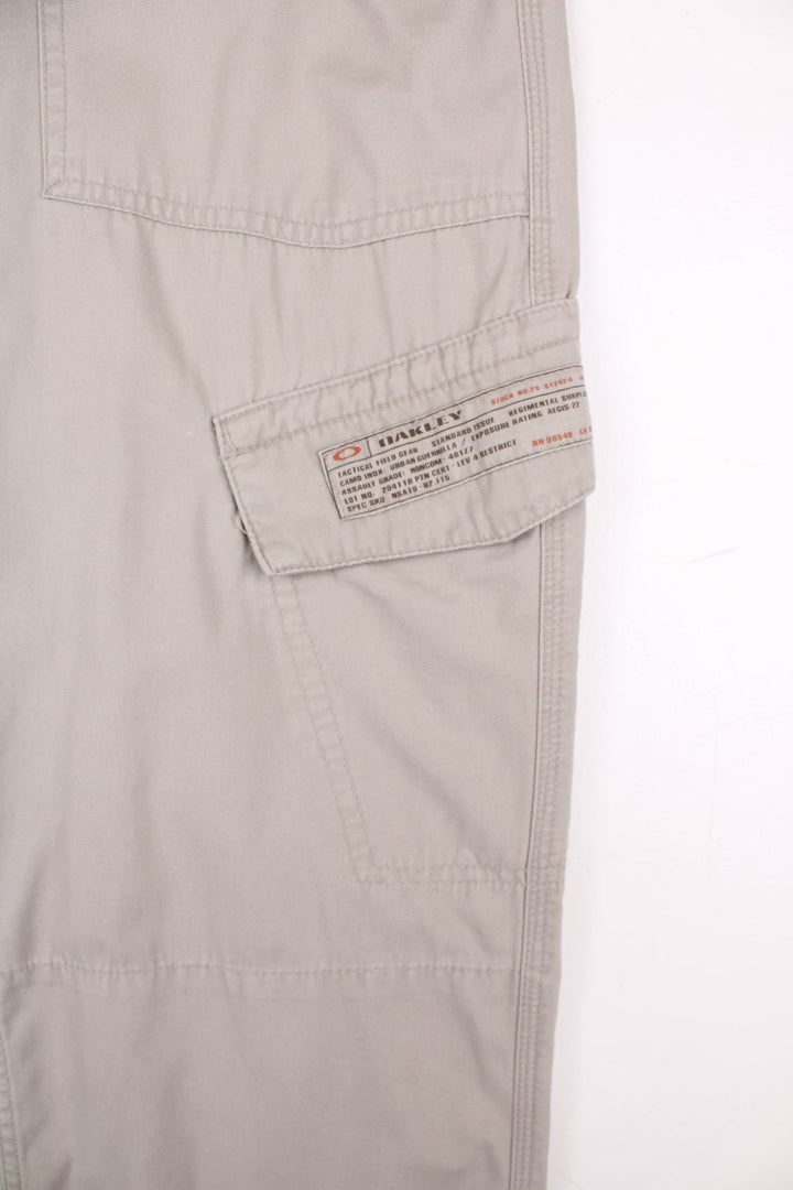 Oakley cargo trousers in tan with multiple pockets, zip and button closure, and a logo patch on the back.