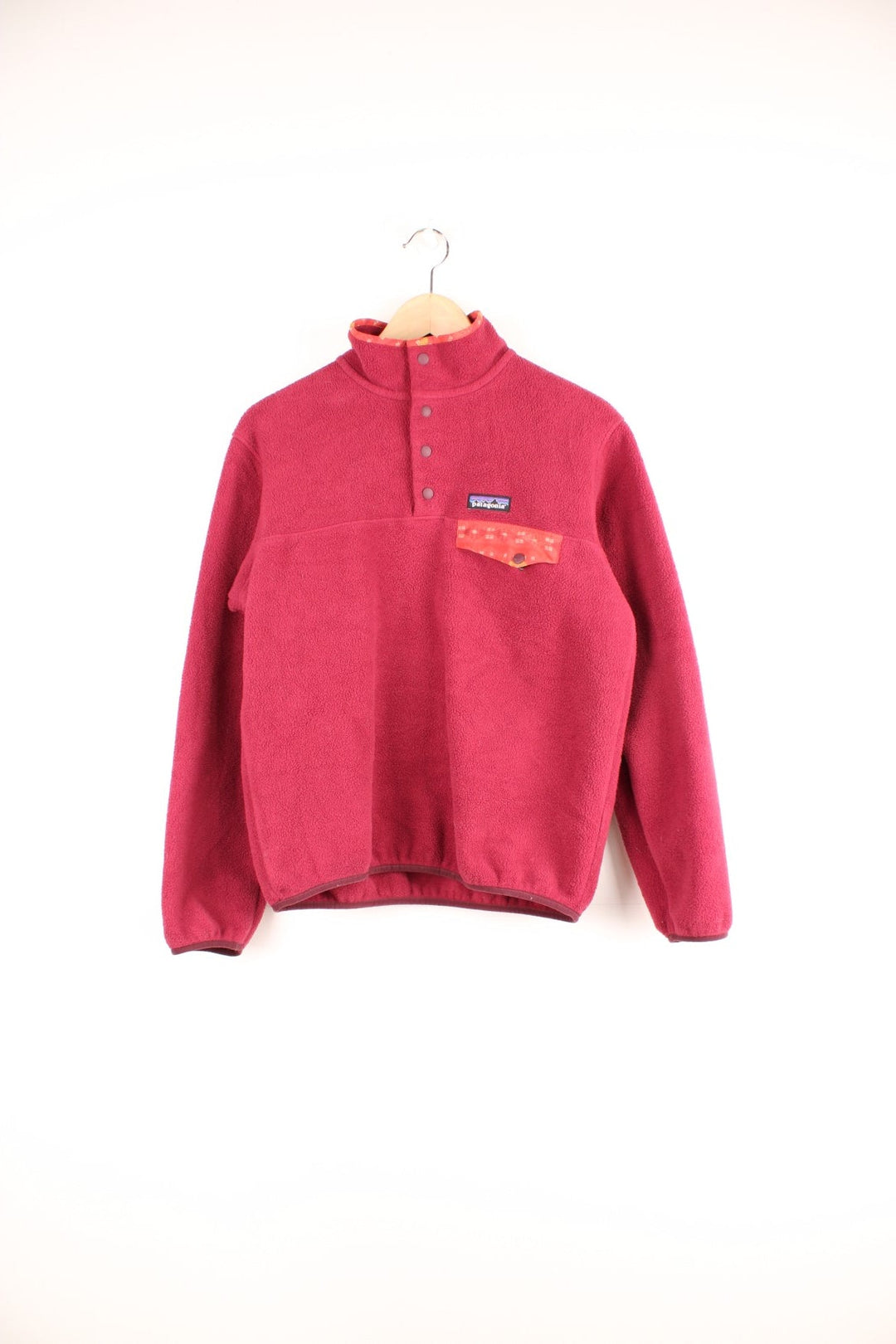 Dark Pink Patagonia Synchilla fleece with 1/4 snap closure, a breast pocket, red patterned detailing on the collar, and an embroidered logo patch.  