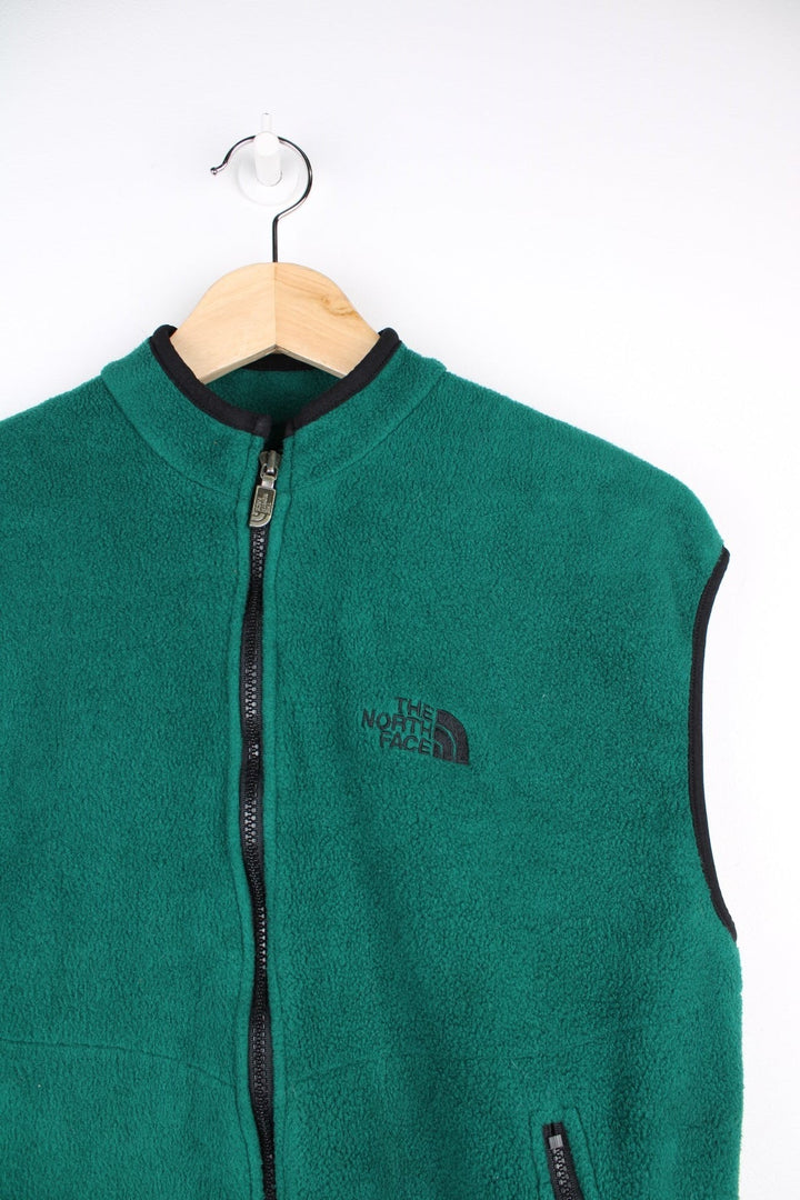 The North Face Sweatshirt in dark forest green with black piping, zip closure, two zipped pockets and an embroidered logo on the chest.