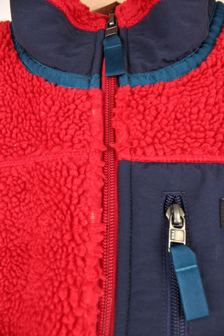 Red Patagonia fleece gilet with blue accents, zip closure, three zipped logos and an embroidered logo patch. 