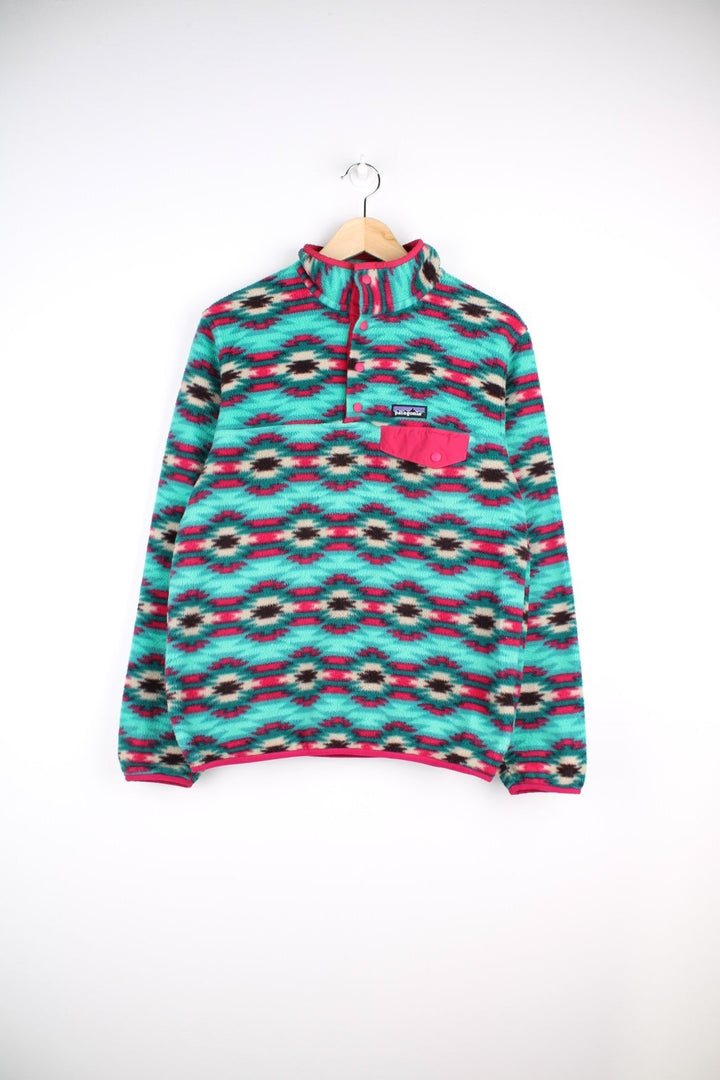 Patagonia fleece in a turquoise blue, pink, and purple pattern with 1/4 snap closure, three pockets, and a small logo on the chest.