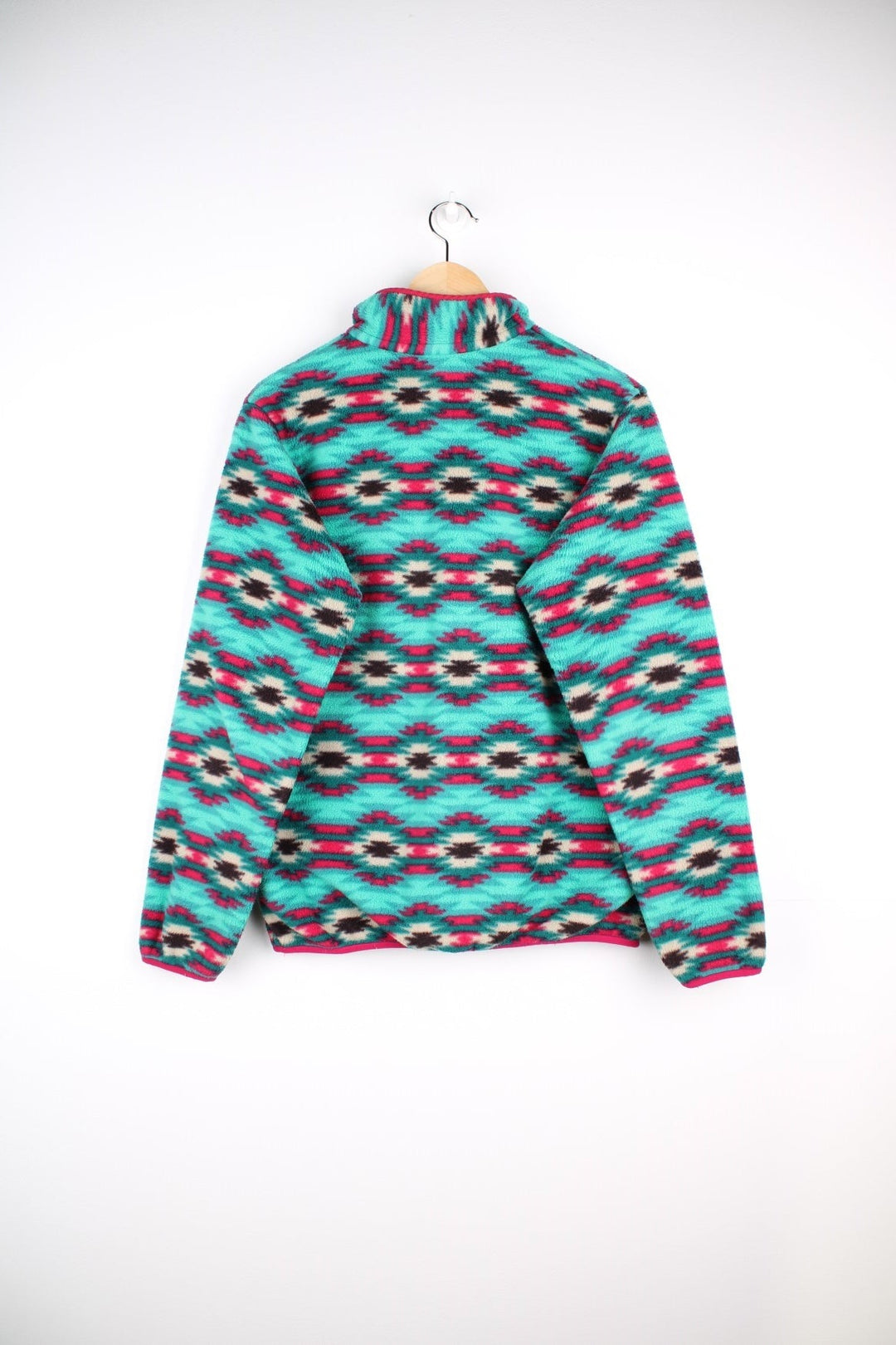 Patagonia fleece in a turquoise blue, pink, and purple pattern with 1/4 snap closure, three pockets, and a small logo on the chest.