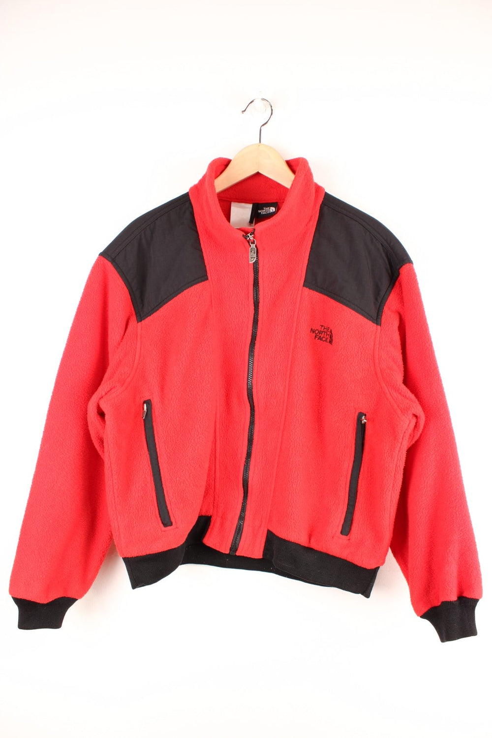 The North Face red zip-up fleece with black accents, two zipped pockets and an embroidered logo. 