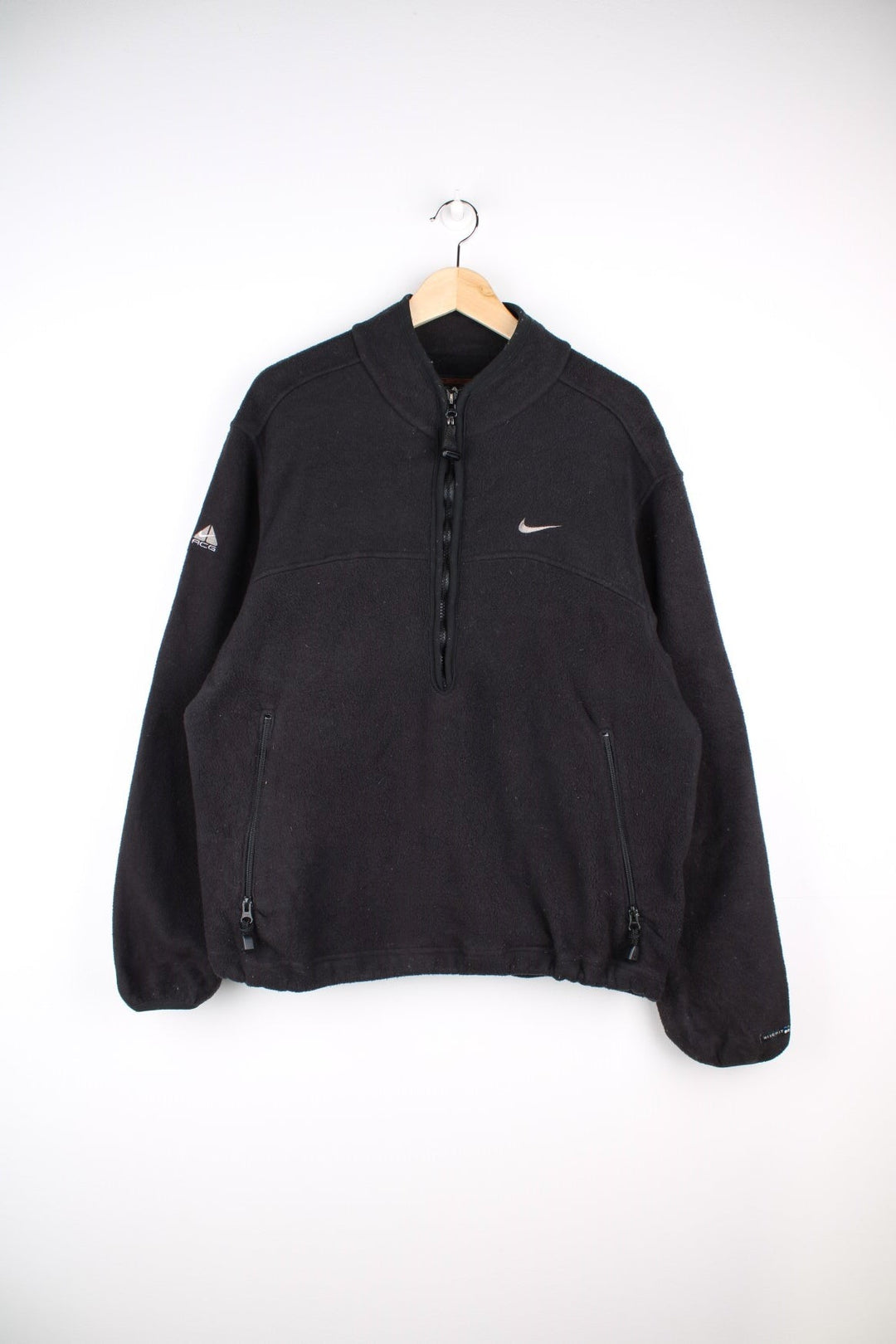 Nike ACG 1/2 zip fleece in black with two zipped pockets, Nike swoosh and ACG logos embroidered on the chest and sleeve respectively, a 'Nike Fit' patch on the cuff and 'All COnditions Gear' patch on the back.