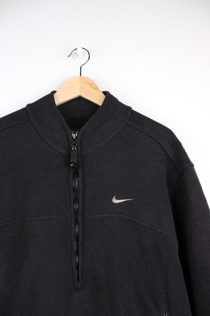 Nike ACG 1/2 zip fleece in black with two zipped pockets, Nike swoosh and ACG logos embroidered on the chest and sleeve respectively, a 'Nike Fit' patch on the cuff and 'All COnditions Gear' patch on the back.