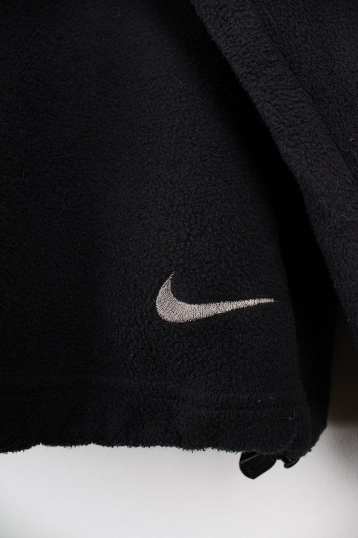 Nike ACG 1/2 zip fleece in black with two zipped pockets, Nike swoosh and ACG logos embroidered on the chest and sleeve respectively, a 'Nike Fit' patch on the cuff and 'All COnditions Gear' patch on the back.