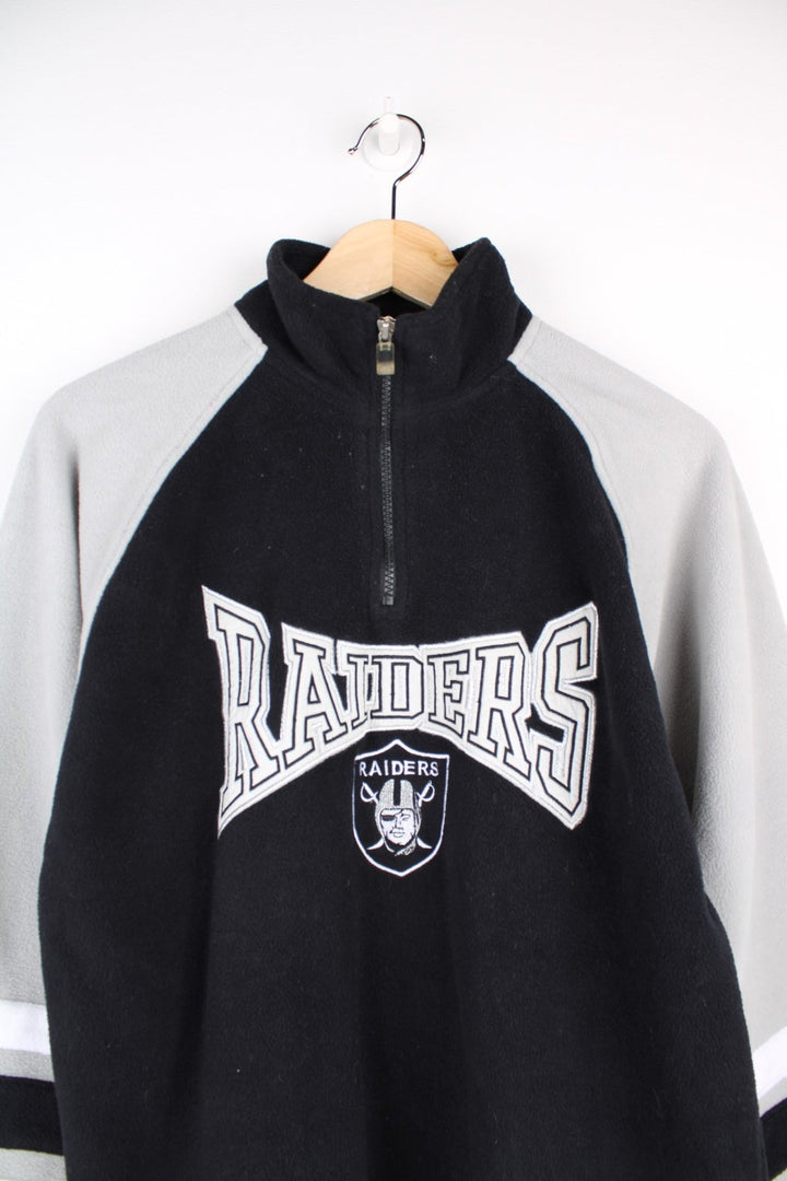 Las Vegas Raiders NFL 1/4 fleece in black with grey sleeves with black and white stripes, and a central team logo graphic 