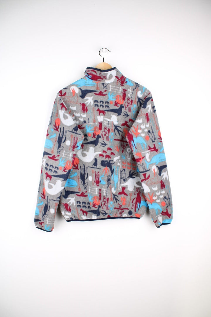 Patagonia fleece in grey with a print of cave painting animals in blue, red and orange, with 1/4 snap closure, one pocket and a small logo on the chest.