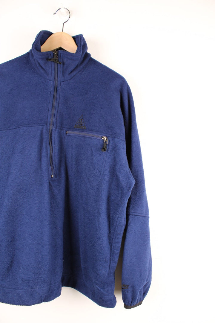 Dark blue Nike ACG 1/2 zip fleece with three pockets and an embroidered logo on the chest and sleeve.  