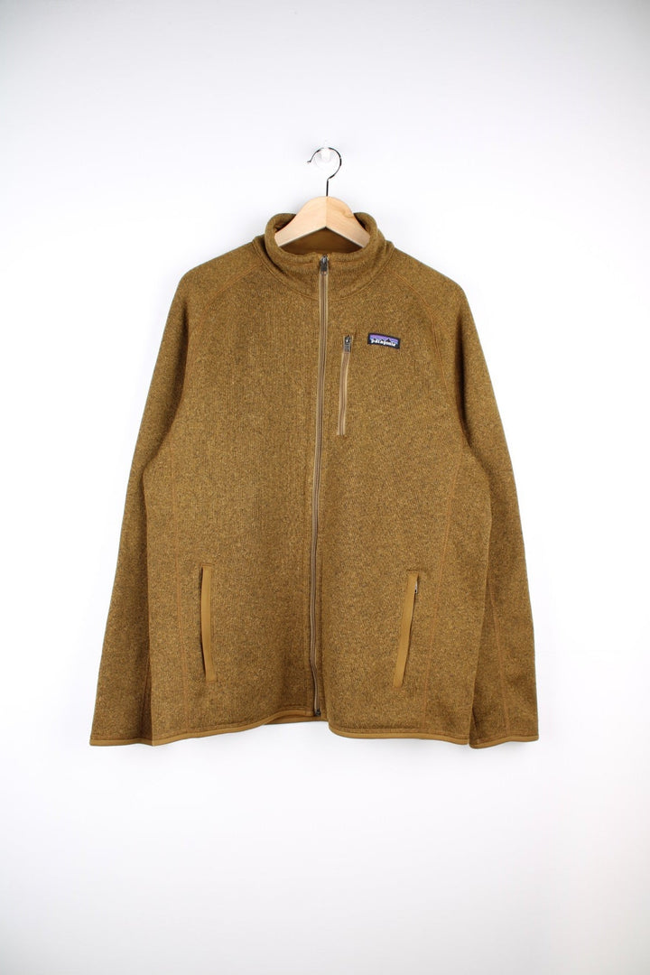 Patagonia zip-through fleece in ochre brown with three zipped pockets and a logo patch on the chest.