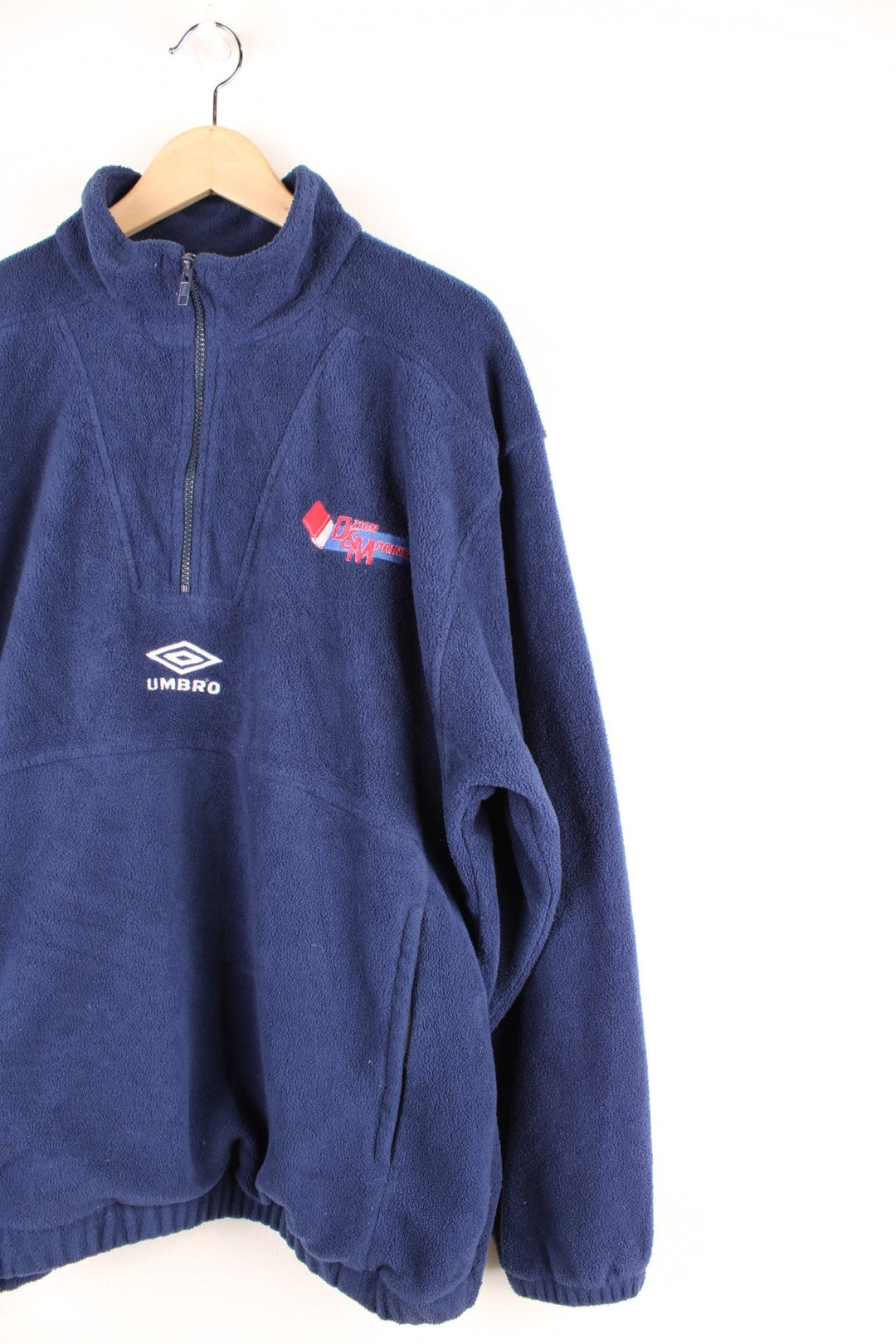 Dark blue Umbro 1/2 zip fleece with two zipped pockets, an embroidered Umbro logo and an embroidered logo in red reading 'DZIGN & MPRINTZ'.