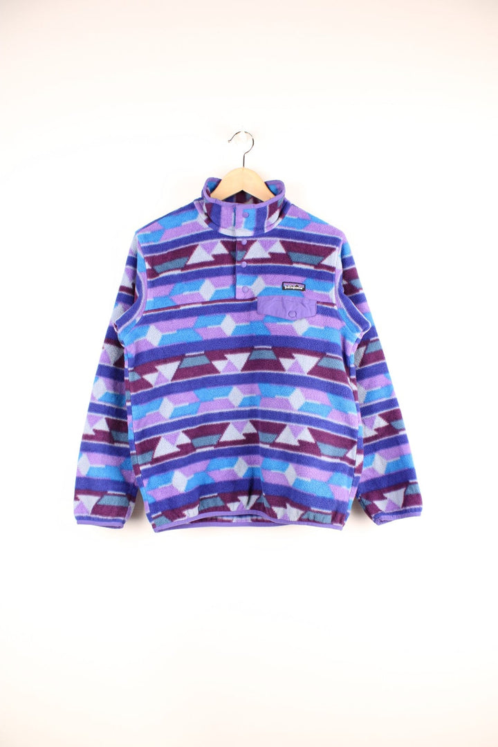 Purple and blue patterned Patagonia Synchilla fleece with 1/4 button closure, a buttoned pocket and an embroidered logo.  