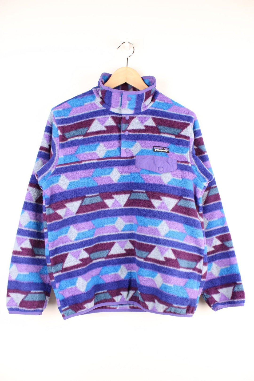 Purple and blue patterned Patagonia Synchilla fleece with 1/4 button closure, a buttoned pocket and an embroidered logo.  