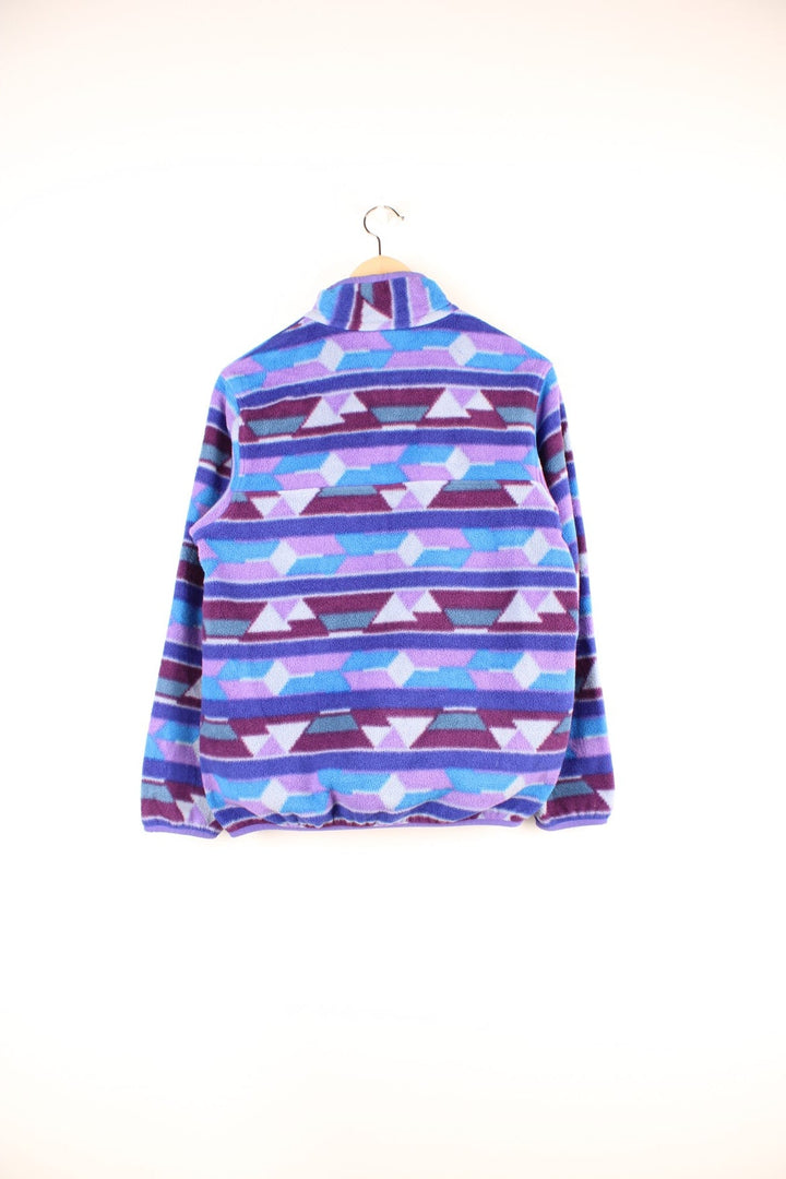 Purple and blue patterned Patagonia Synchilla fleece with 1/4 button closure, a buttoned pocket and an embroidered logo.  