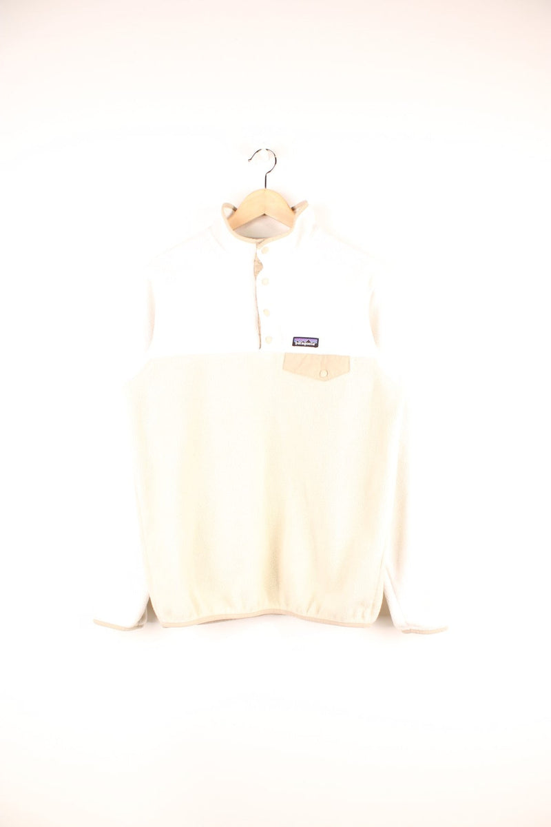 White and tan Patagonia Synchilla 1/4 button fleece with one breast pocket and an embroidered logo. 