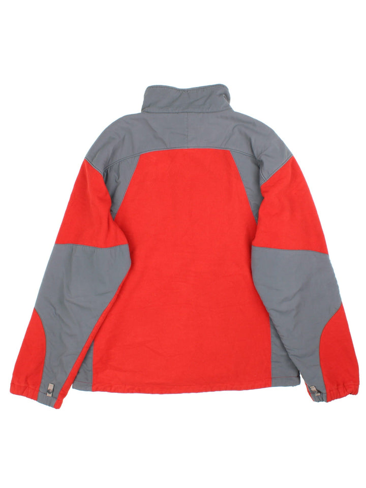 The North Face Fleece in a red colourway with grey panelling down the sides and shoulders, Full zip with multiple pockets and classic small logo on the front.