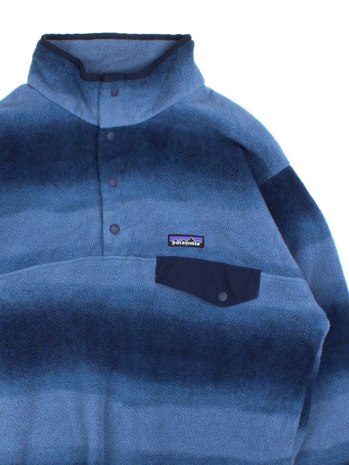 Vintage Patagonia Synchilla Fleece in a blue colourway.1/4 Button up with buttoned pocket and small classic logo on the front. Blue multitone pattern across the whole fleece.