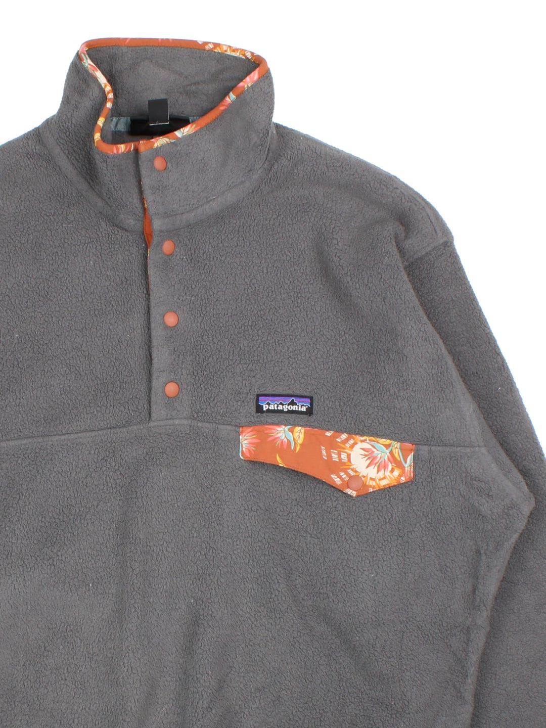 Patagonia Synchilla Fleece in a grey colourway with orange trimming. 1/4 Buttons up and has button pocket on the front with the small classic logo above. 