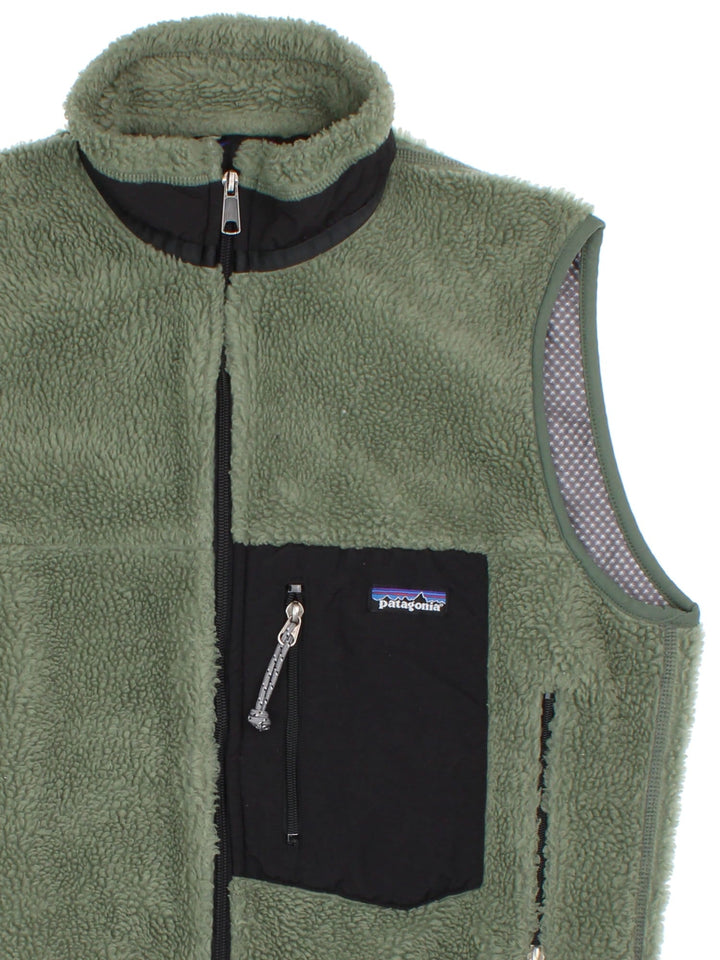 Patagonia Fleece Gilet in a green colourway with black pocket patch. Full zip with multiple zip pockets and small classic logo on the front.