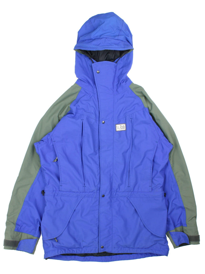 Vintage Rab Heavy Jacket in a blue colourway. Multiple pockets with zips and drawstring at the hip, Green panelling down shoulders and arms.