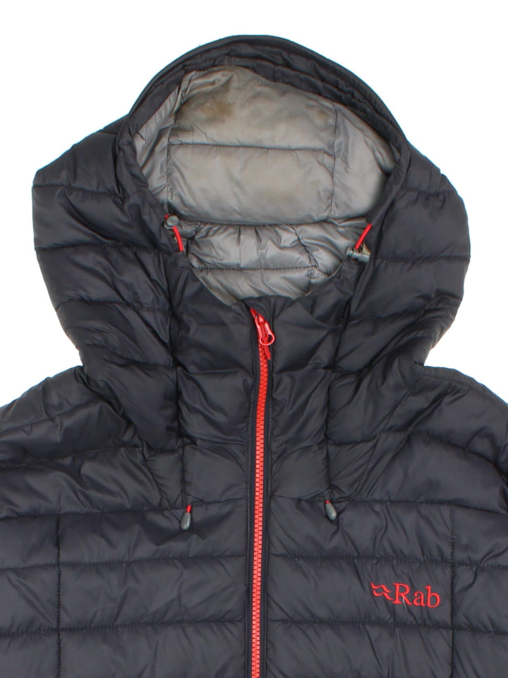 Rab Nebula Puffer Coat in a black colourway. Full red zip detail and multiple pockets on front with a drawstring hood.