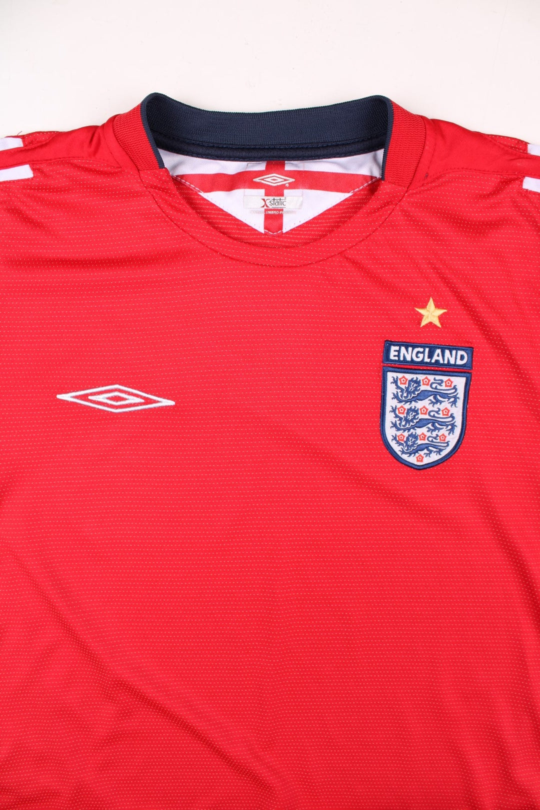 England 2004/06 Umbro Football Shirt in the red away kit colourway, features embroidered logos and badge on the front.