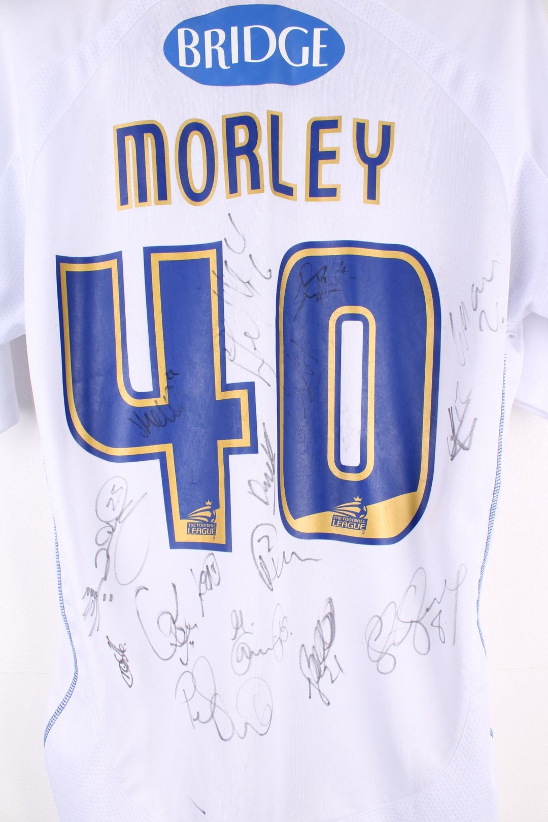 Vintage Bury FC 2012/13 Football Shirt in the white and blue home kit colourway, features embroidered logo and badge on the front, and on the back has Morley number 40 printed alongside team signatures.