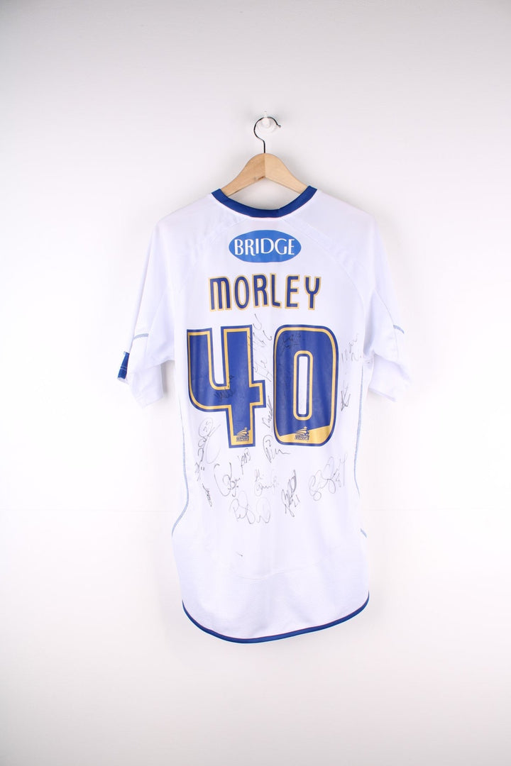 Vintage Bury FC 2012/13 Football Shirt in the white and blue home kit colourway, features embroidered logo and badge on the front, and on the back has Morley number 40 printed alongside team signatures.