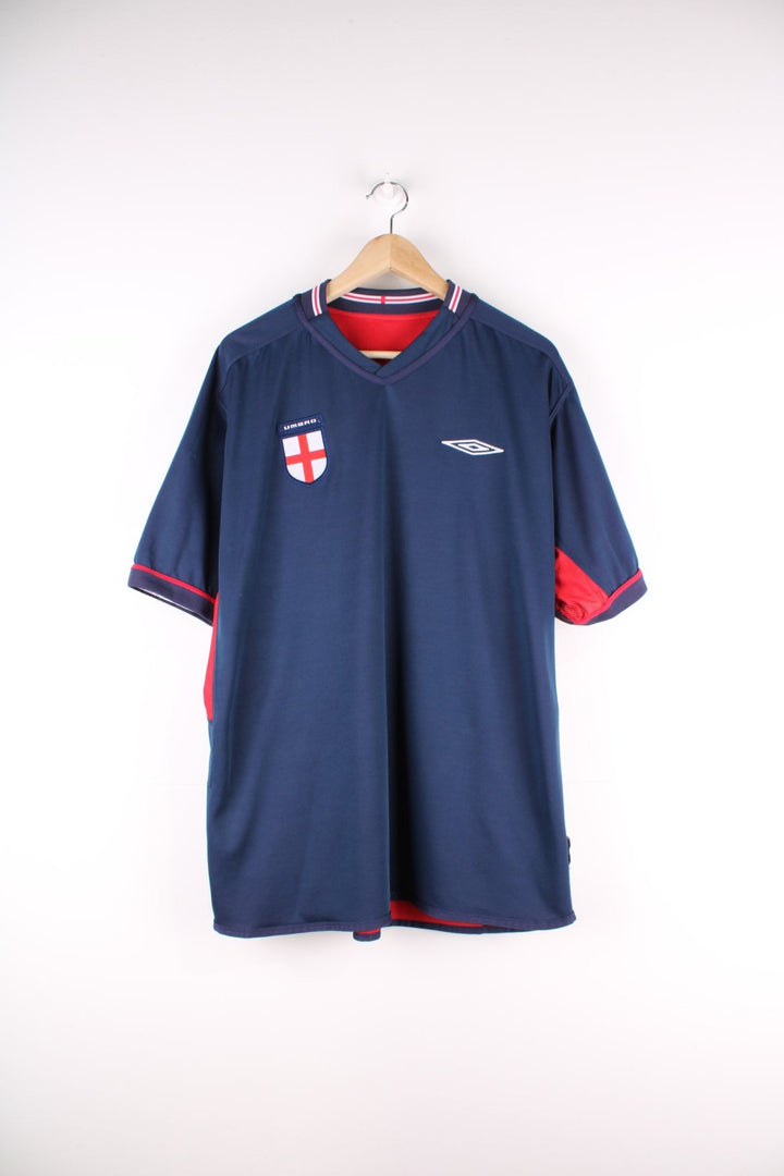 England 2002/04 Reversible Umbro Football Shirt in either a red or blue away kit colourway options, features embroidered logo and badge on the front.