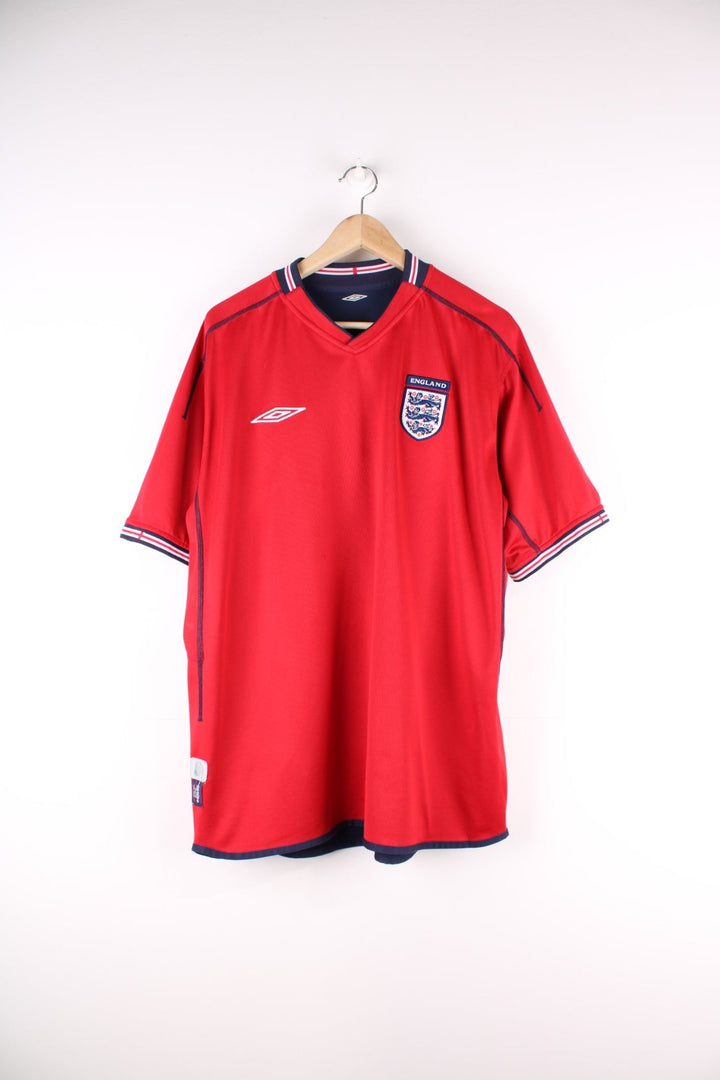 England 2002/04 Reversible Umbro Football Shirt in either a red or blue away kit colourway options, features embroidered logo and badge on the front.