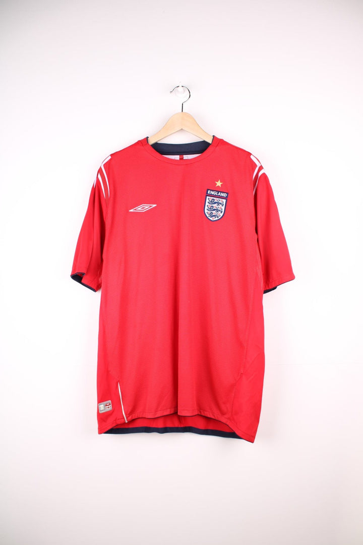 England 2004/06 Umbro Football Shirt in the red away colourway, features embroidered logo and badge on the front.