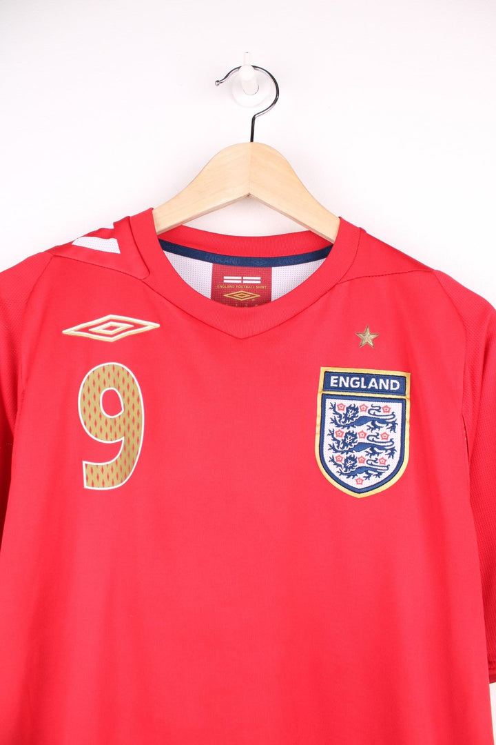 England 2006/08  Football Shirt in the  away colourway, features embroidered logo and badge on the front, and has Wayne Rooney number 9 printed on the back.