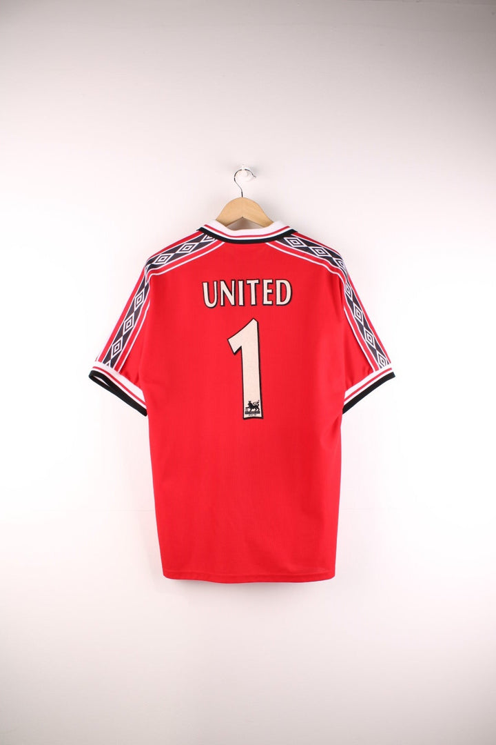 Manchester United 1998/99  Football Shirt in the  home kit colourway, features embroidered logos and badge on the front, zip up collar, and United number 1 printed on the back.