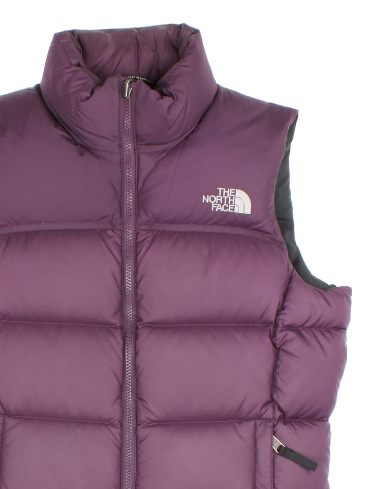 The North Face Down Puffer Gilet in a purple colourway. Zips up and has side pockets, insulated lining, and has the logo embroidered on the front and back.