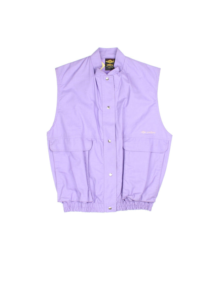 Vintage Umbro Utility Vest in a purple colourway. Buttons up and has side pockets, and the logo embroidered on the front.