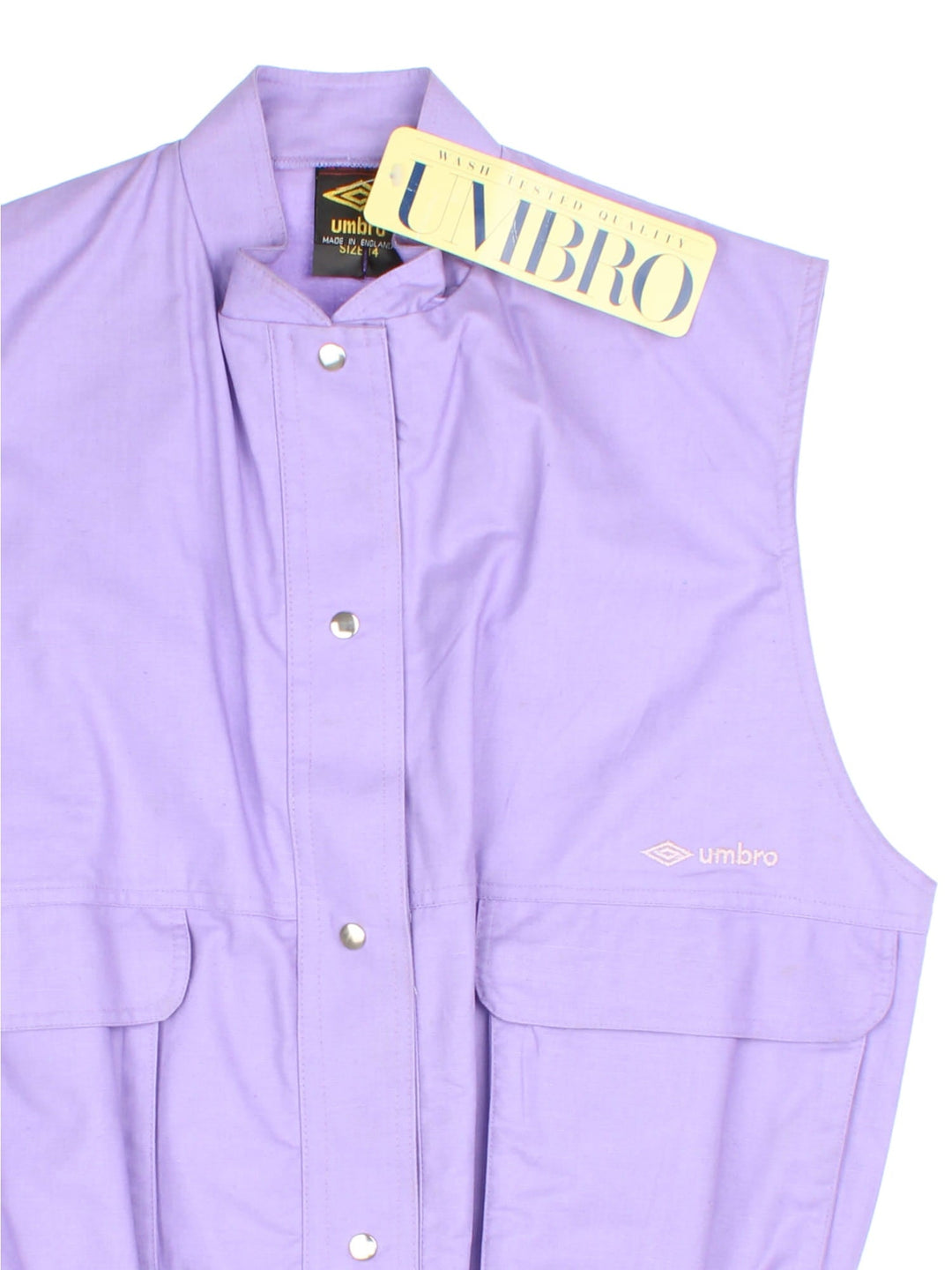 Vintage Umbro Utility Vest in a purple colourway. Buttons up and has side pockets, and the logo embroidered on the front.