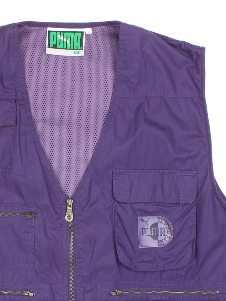 Vintage Puma Pursuit Utility Vest in a purple colourway. Zips up and has multiple pockets, mesh lining, and has the logo embroidered on the front.