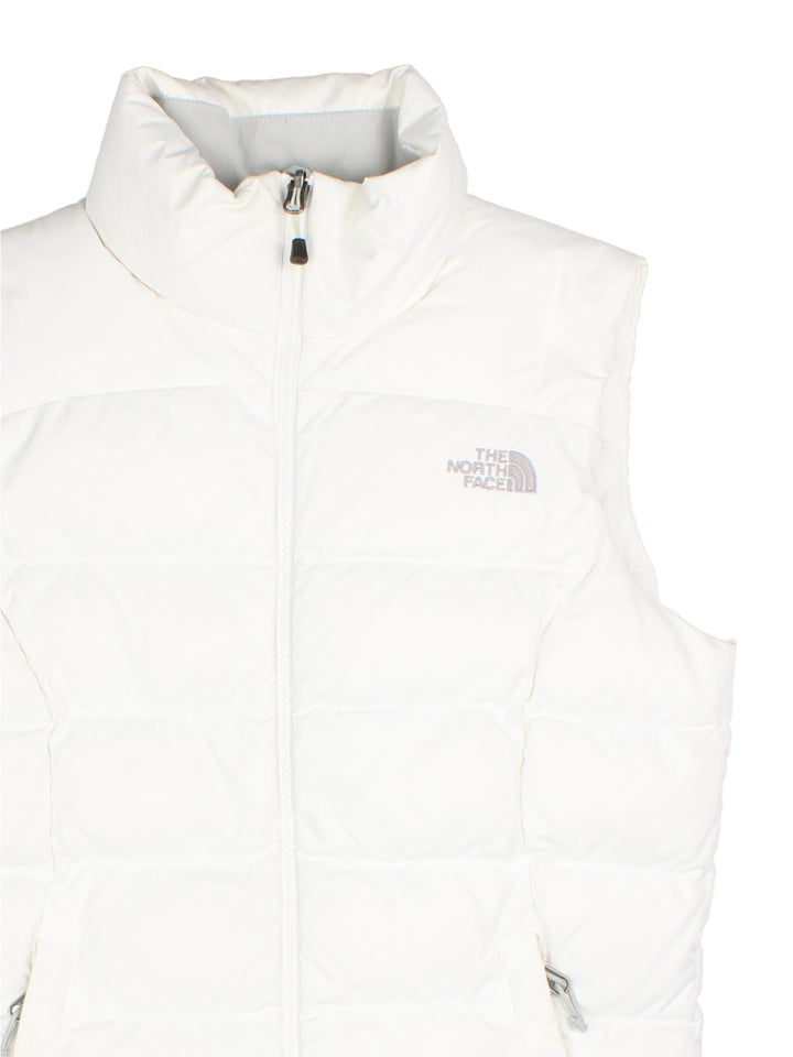 The North Face Down Puffer Gilet in a white colourway. Zips up and has side pockets, insulated lining, and has the logo embroidered on the front and back.