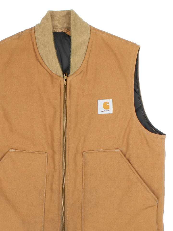 Vintage 80's Carhartt Gilet in a tan colourway. Zips up and has side pockets, insulated with a quilted lining, and has the logo embroidered on the front.