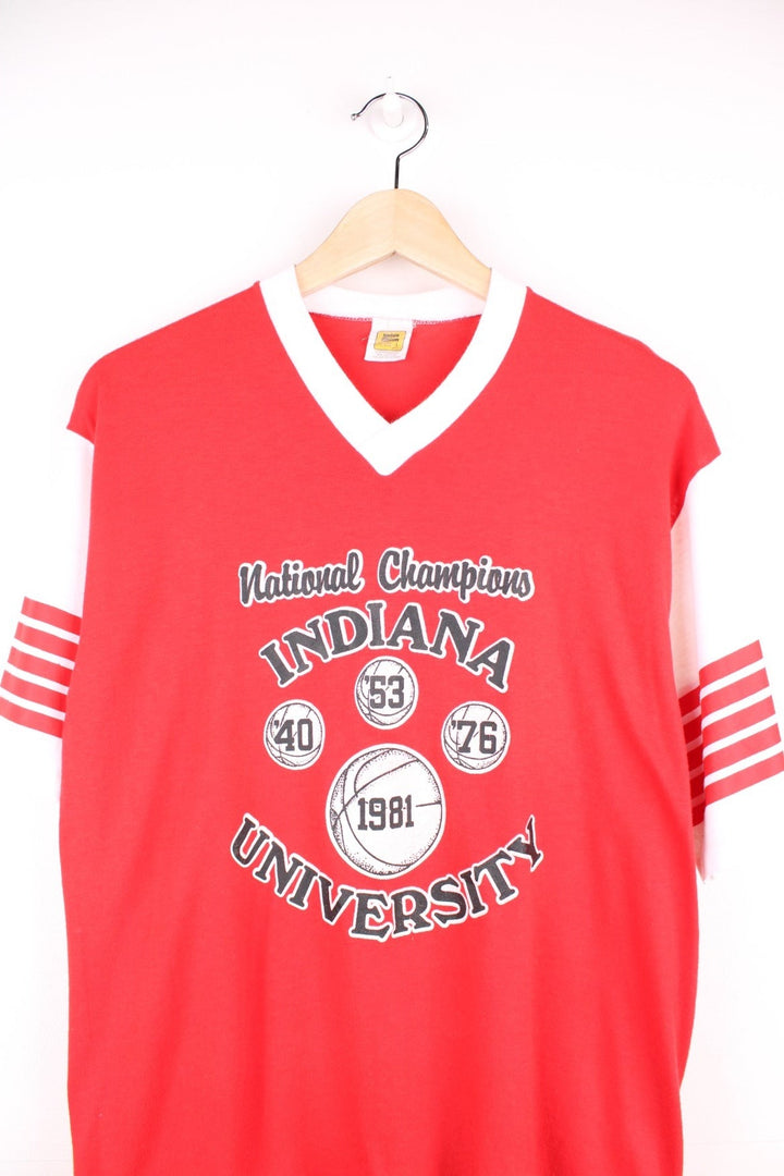 Vintage 80's Indiana University National Basketball Champions T-Shirt in a red and white colourway, has a v neck collar, stripes going around the sleeves and the team spell out logo with basketball graphic printed on the front. 